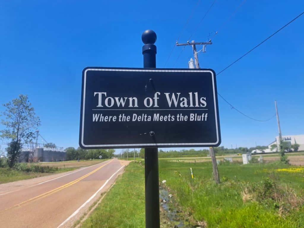 Town of Walls, MS sign with a rural landscape and open roads, highlighting the area's natural beauty. Expert lawn care services available in Walls and surrounding Mid-South communities.