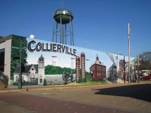 Collierville, TN mural featuring historic landmarks, a steam train, and a water tower, showcasing the town's rich heritage. Professional lawn care services available in Collierville and surrounding Mid-South areas.